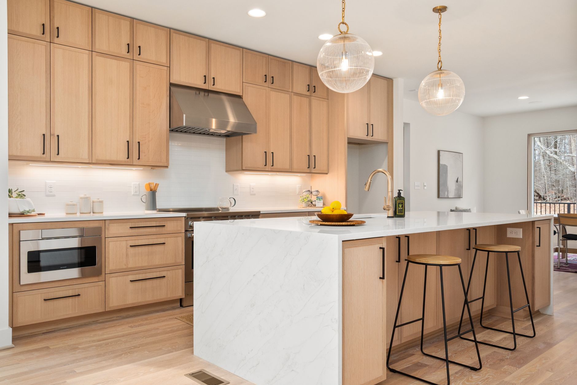 House on the Dune — kitchen with wood cabinets and marble island under warm pendant light